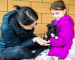 An adult and child playing with a puppy