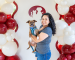 person holding a dog in front of red and white balloons